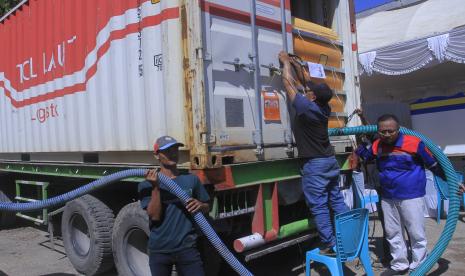 Petugas mengisi minyak goreng curah ke dalam mobil tangki yang diambil dari satu unit kontainer usai acara pendistribusian minyak goreng curah dan gula pasir di Kupang, NTT, Rabu (11/5/2022). BUMN Holding pangan ID FOOD bersama Kementerian Perhubungan, Badan Pangan Nasional, PTPN Group, Pos Indonesia dan BRI bersinergi mulai mendistribusikan 800 ton gula pasir dan 300 ton minyak goreng curah ke pasar - pasar tradisional di Kupang.