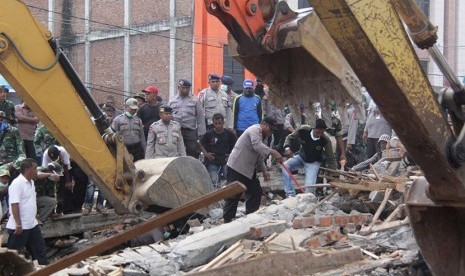 Petugas mengoperasikan alat berat untuk mencari korban yang tertimpa reruntuhan bangunan rumah toko (ruko) akibat gempa di Desa Ulee Glee, Kecamatan Bandar Dua, Kabupaten Pidie Jaya, Aceh, Rabu (7/12). 