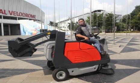 Petugas mengoperasikan mesin pembersih jalan dari PT Kobexindo Tractors Tbk (KOBX) di sekitar stadion Velodrome, Rawamangun, Jakarta Timur, Jumat (10/12).