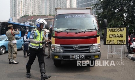 Petugas menilang pengendara mobil yang melanggar aturan pembatasan kendaraan sistem ganjil genap di MH Thamrin, Jakarta Pusat, Selasa (30/8). (Republika/Yasin Habibi)