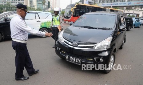 Petugas menilang pengendara mobil yang melanggar aturan pembatasan kendaraan sistem ganjil genap di MH Thamrin, Jakarta Pusat, Selasa (30/8). (Republika/Yasin Habibi)