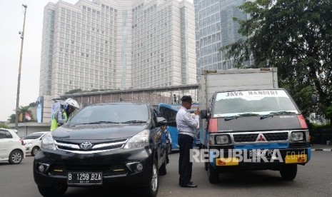 Petugas memberhentikan mobil yang melanggar aturan pembatasan kendaraan sistem ganjil genap (ilustrasi)