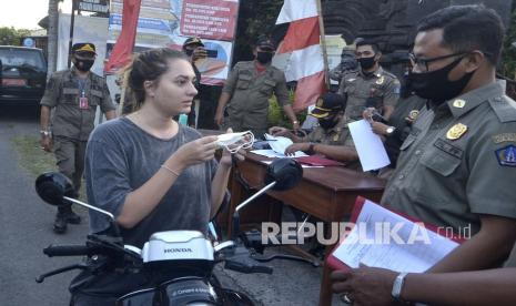 Petugas menindak warga negara asing yang tidak mengenakan masker saat kegiatan penerapan disiplin dan penegakan hukum protokol kesehatan, di kawasan Pererenan, Badung, Bali, Selasa (8/9/2020). Pemkab Badung mulai menerapkan sanksi berupa denda administratif sebesar Rp.100 ribu kepada masyarakat yang tidak menggunakan masker saat beraktivitas dan berkegiatan di luar rumah termasuk bagi wisatawan mancanegara yang berada di wilayah Badung.