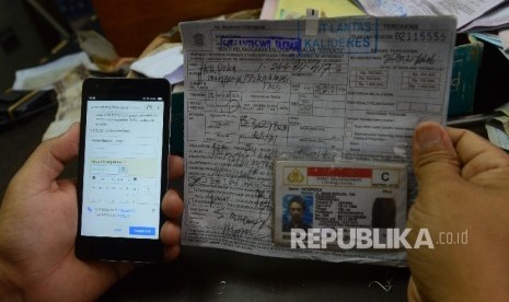  Petugas menunjukan aplikasi sidang online serta berkas tilang pelanggar lalu lintas di Kejaksaan Negeri Jakarta Barat, Jumat (29/1). (Republika/Raisan Al Farisi) 