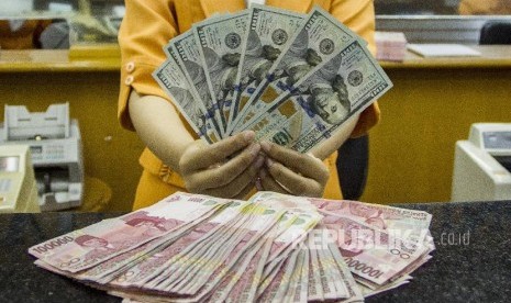 Petugas menunjukan pecahan uang dolar Amerika Serikat dan rupiah di salah satu gerai penukaran mata uang asing, di Jakarta (ilustrasi)