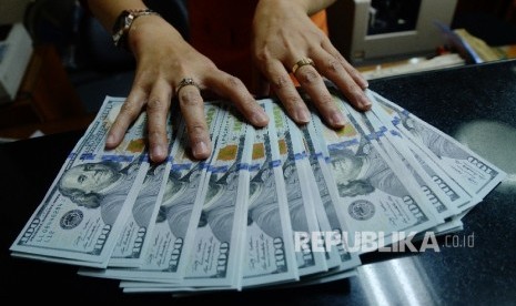 Petugas menunjukan uang dolar AS di tempat penukaran uang asing. ilustrasi.