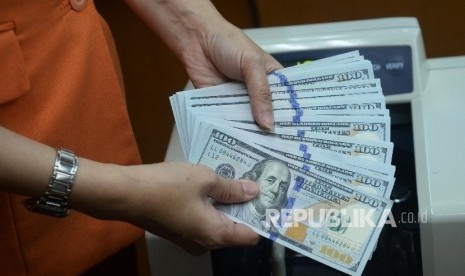 Petugas menunjukan uang dolar AS di tempat penukaran uang Ayu Masagung, Jakarta, Rabu (4/10).