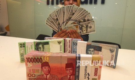 Petugas menunjukkan pecahan mata uang dolar AS dan rupiah di Plaza Mandiri, Jakarta. ilustrasi