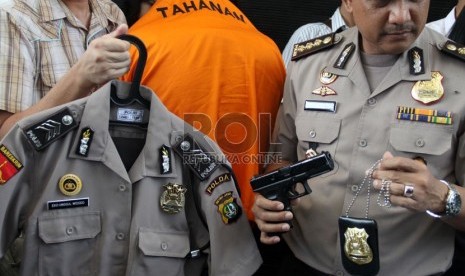   Petugas menunjukkan tersangka polisi gadungan beserta seragam dan lencana polisi di Polda Metro Jaya, Jakarta (Republika/Yasin Habibi)