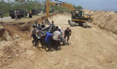 Petugas menurunkan jenazah korban gempa tsunami Palu untuk dimakamkan di Poboya, Mantikulore, Palu, Senin (1/10).