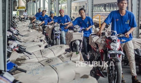 Petugas menurunkan paket sepeda motor program angkutan sepeda motor gratis (motis).