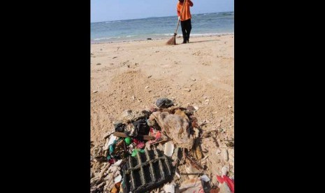 Petugas menyapu sampah-sampah yang mengotori pantai. (ilustrasi) 