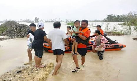 Petugas menyelamatkan warga yang terjebak banjir bandang di rumahnya di Negros, Filipina.