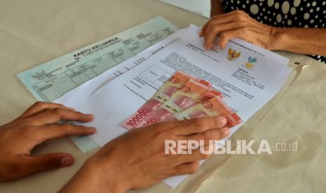 Petugas menyerahkan uang tunai saat penyaluran bantuan sosial tunai (BST) Kantor Pos (ilustrasi).