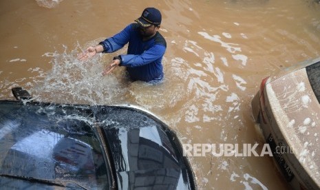  Petugas menyiram kendaraan terjebak banjir di parkir basement di Jalan Kemang Raya, Jakarta, Ahad (28/8)(Republika/Wihdan)