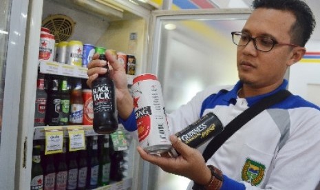 Petugas merazia minuman beralkohol yang dijual di sebuah minimarket di Kota Madiun, Jumat (30/1).