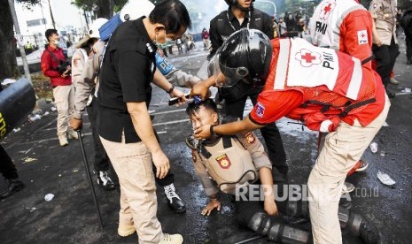 Petugas Palang Merah Indonesia (PMI) Kota Bandung mengevakuasi petugas kepolisian yang terkena gas air mata saat Aksi Tolak RUU Bermasalah di Jalan Diponegoro, Kota Bandung.