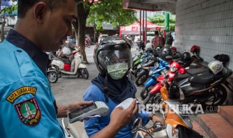 Petugas parkir menggunakan alat transaksi parkir elektronik. 