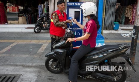 Petugas parkir menjelaskan kepada warga penggunaan sistem layanan parkir berbasis elektronik E-Parkir usai acara Launching Sistem parkir elektronik berbasis e-Money di jalan Gatot Subroto, Solo, Jawa Tengah, Jumat (4/8).