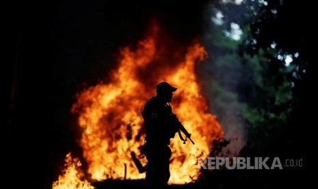 Petugas patroli dengan latar kobaran api yang membakar truk pengangkut kayu milik pelaku ilegal logging di Hutan Amazon Brazil