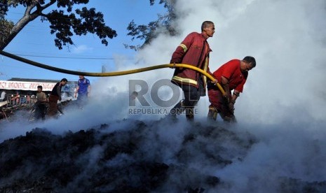   Petugas pemadam kebakaran berada di antara kepulan asap bekas api yang telah membakar gudang kayu dan bengkel mebel di Cimanggis, Depok, Jawa Barat, Senin (18/3).  (Republika/Rakhmawaty La'lang)