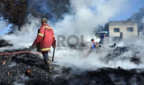  Petugas pemadam kebakaran berada di antara kepulan asap bekas api yang membakar gudang kayu dan bengkel mebel di Cimanggis, Depok, Jawa Barat, Senin (18/3).  (Republika/Rakhmawaty La'lang)