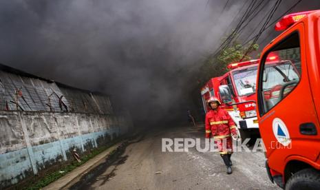 Petugas pemadam kebakaran berjalan di kawasan pabrik terbakar (ilustrasi). Kebakaran besar melanda gudang biji plastik milik PT Plasindo di Jalan Kamal Raya, Kelurahan Tegal Alur, Kalideres, Jakarta Barat, Selasa (8/6) malam. Amukan Si Jago Merah yang melahap area seluas 3.000 meter persegi itu mengakibatkan kerugian sekitar Rp 3 miliar. 