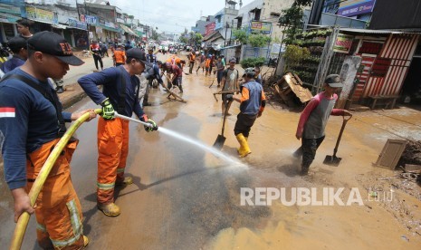 Petugas pemadam kebakaran bersama warga bergotong-royong membersihkan lumpur sisa banjir bandang yang memenuhi Jalan di kawasan Cicaheum, Kota Bandung, Rabu (21/3).