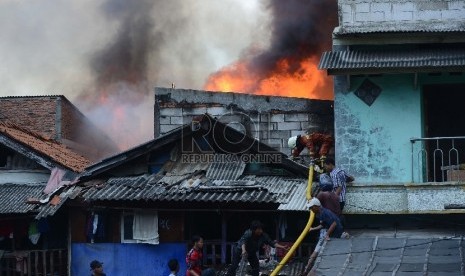 Petugas pemadam kebakaran bersama warga berusaha untuk memadamkan api yang membakar salah satu rumah di Kawasan Kebon Pala, Penjaringan, Jakarta Utara, Rabu (11/3).  (Republika/Raisan Al Farisi)