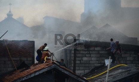 Petugas pemadam kebakaran bersama warga berusaha untuk memadamkan api yang membakar salah satu rumah di Kawasan Kebon Pala, Penjaringan, Jakarta Utara, Rabu (11/3).  (Republika/Raisan Al Farisi)