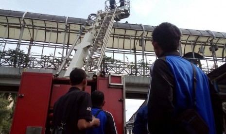 Petugas pemadam kebakaran berupaya menyelamatkan seorang pria yang ingin melakukan bunuh diri dari atap Jembatan Penyeberangan Orang (JPO) di depan Gedung Bank Indonesia, Jln MH Thamrin, Sabtu (25/3).