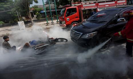 Petugas pemadam kebakaran berusaha memadamkan api dari kendaraan yang mengalami kecelakaan saat simulasi penanganan kecelakaan lalu lintas, ilustrasi