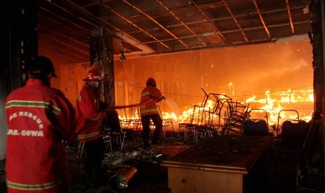 Petugas pemadam kebakaran berusaha memadamkan api saat kebakaran di kantor DPRD Kabupaten Gowa, Sulawesi Selatan, Senin (26/9).