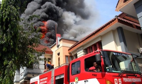 Petugas pemadam kebakaran berusaha memadamkan api saat kebakaran di kantor DPRD Kabupaten Gowa, Sulawesi Selatan, Senin (26/9). 