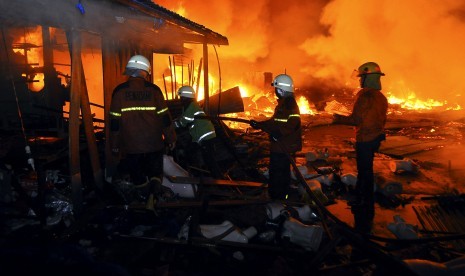 Petugas pemadam kebakaran berusaha memadamkan api yang membakar kios pedagang di Pasar Cik Puan, Kota Pekanbaru, Riau, Senin malam (6/7).