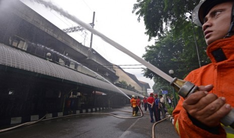 Petugas pemadam kebakaran berusaha memadamkan api yang membakar sebuah restoran cepat saji di Stasiun Gambir, Jakarta Pusat, Jumat (27/12). 