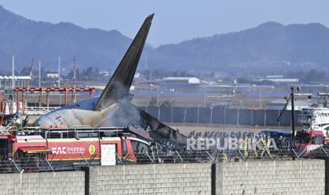 Petugas pemadam kebakaran dan anggota tim penyelamat bekerja di landasan pacu Bandara Internasional Muan di Muan, Korea Selatan, Ahad, 29 Desember 2024 untuk menyelamatkan dan mengevakuasi penumpang pesawat Boeing 737-800 milik Maskapai Jeju Air yang terbakar dan meledak setelah menabrak dinding usai mendarat..