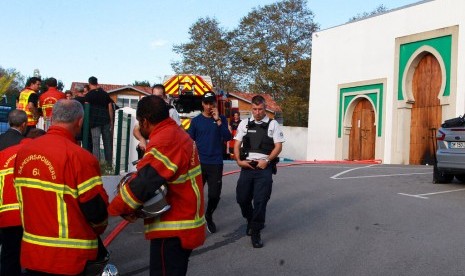 Petugas pemadam kebakaran dan polisi berjaga di luar masjid di Bayonne, Prancis setelah penembakan dan pembakaran masjid, Senin (28/10).