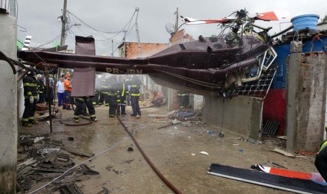   Petugas pemadam kebakaran di lokasi jatuhnya helikopter yang menabrak kaawasan pemukiman di Sao Paulo, Brasil, Senin (21/1).  (AP/Andre Penner)