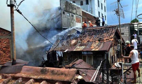  Petugas Pemadam kebakaran dibantu warga berusaha memadamkan rumah yang terbakar di Jalan Salemba, Senen, Jakarta Pusat, Selasa (12/3).   (Republika/ Agung Supriyanto)