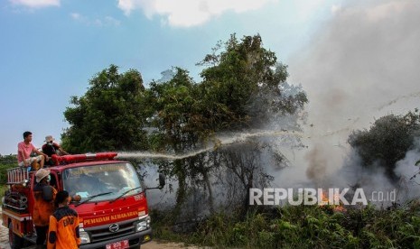 Petugas Pemadam Kebakaran Kota Pekanbaru bersama BPBD Pekanbaru menyemprotkan air saat memadamkan kebakaran lahan gambut di Pekanbaru, Riau, Jumat (2/8/2019). 