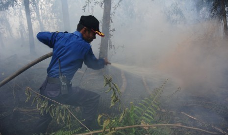 Petugas pemadam kebakaran Kota Pontianak memadamkan api yang merambat di bawah tanah lahan gambut di Jalan Parit Haji Husin II, Pontianak, Kalbar, Senin (22/8). 