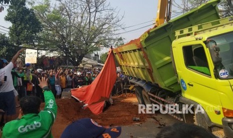 Petugas pemadam kebakaran Kota Tangerang dibantu warga melakukan evakuasi bangkai mobil saat terjadi kecelakaan maut antara truk pengangkut tanah dengan minibus daihatsu sigra yang hancur tak terbentuk akibat tertindih badan truk di Karawaci, Tangerang, Banten, Kamis (1/8/2019).