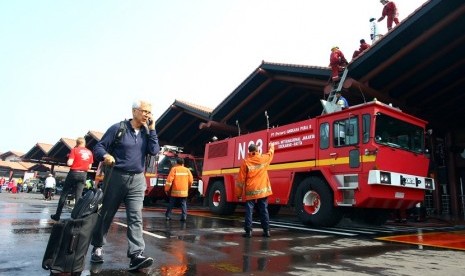 Petugas pemadam kebakaran melakukan pendinginan Gate 3 keberangkatan Luar Negeri yang terbakar di Terminal 2E Bandara Soekarno Hatta, Tangerang, Banten, Minggu (5/7). Kebakaran yang menghanguskan ruang tunggu Terminal 2E masih dalam penyelidikan pihak berw