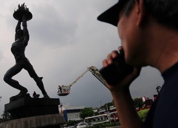 Petugas Pemadam Kebakaran membersihkan Patung Pemuda Membangun di Bundaran Senayan, Jakarta Selatan, Ahad (26/2). (Republika/Aditya Pradana Putra)