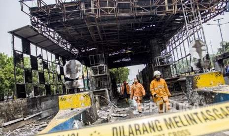 Petugas pemadam kebakaran memeriksa bangunan yang terbakar usai dipadamkan di Gardu Tol Pejompongan, Jakarta, Kamis (27/9).