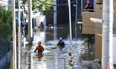 Petugas pemadam kebakaran memeriksa kawasan yang dilanda banjir akibat Topan Hagibis di Kawasaki, dekat Tokyo, Jepang, Ahad (13/10).