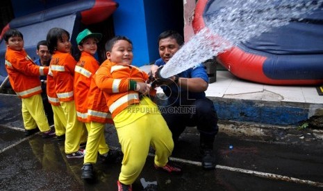  Petugas pemadam mendampingi siswa TK melakukan latihan pemadaman api saat kunjungan belajar ke markas pemadam kebakaran di Jalan Matraman Raya, Jakarta Timur, Senin (12/2).  (Republika/Prayogi)