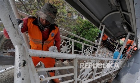 Petugas Penanganan Prasarana dan Sarana Umum (PPSU) mengecat Jembatan Penyeberangan Orang (JPO) di Jalan KH. Abdullah Syafei, Tebet, Jakarta Selatan, Selasa (26/9). 