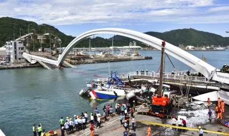 Petugas penyelamat bekerja di lokasi ambruknya jembatan di sebuah pelabuhan di Nanfangao, timur Taiwan, Selasa (1/10). Jembatan ambruk ketika sebuah truk tanker melintas dan menimpa sebuah kapal di bawahnya. 